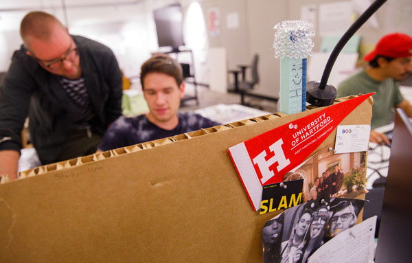 Students working in studio with UHart flag on desk