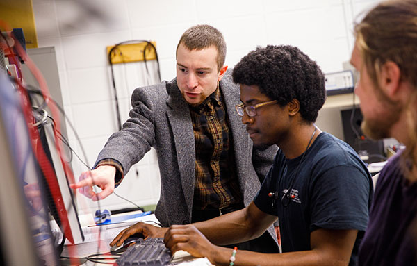 students and faculty member working on computer