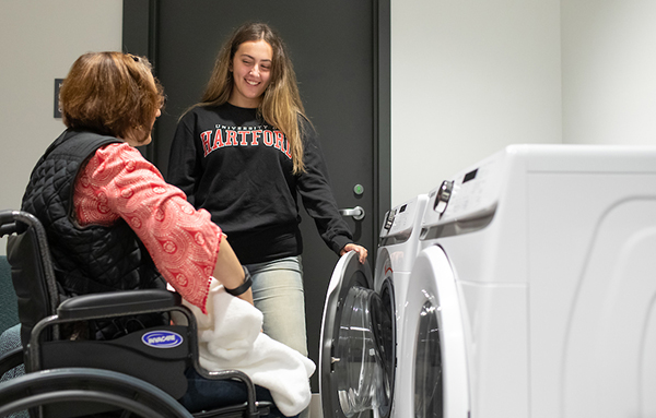 student helping client with laundry