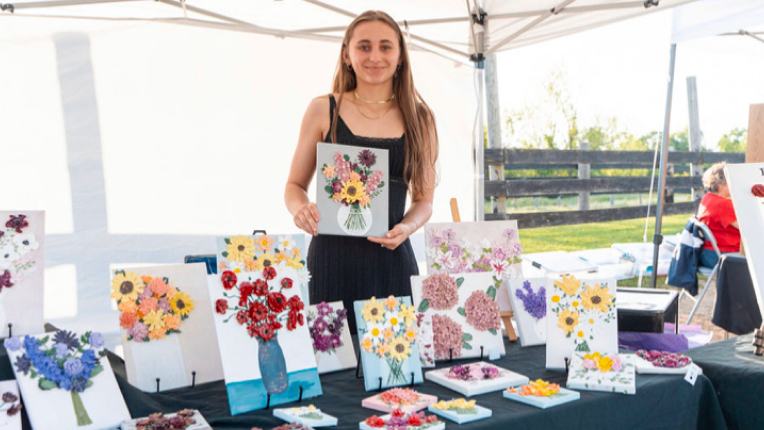 image of owner Kalle Legassey at a craft table showing her flower designs