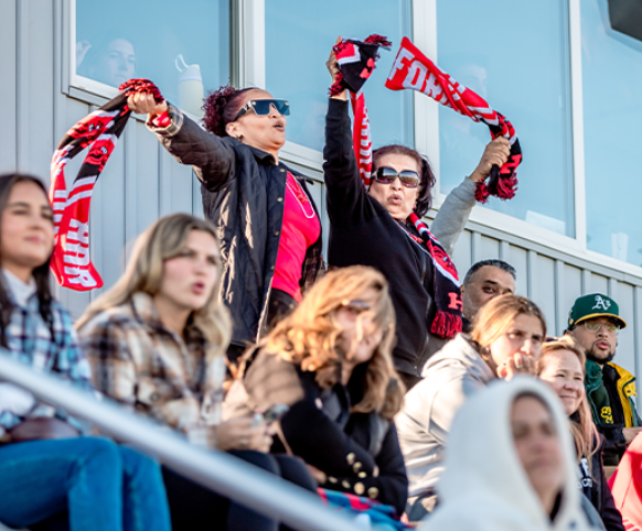 2 alumni cheering at a Uhart sports game 