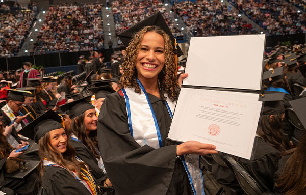 UHart student at commencement holding diploma