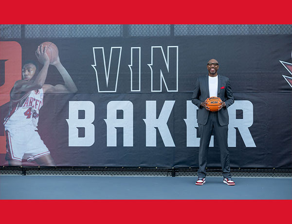 Vin Baker holding a basketball in front of the Vin Baker Outdoor Athletics and Recreation Complex at UHart